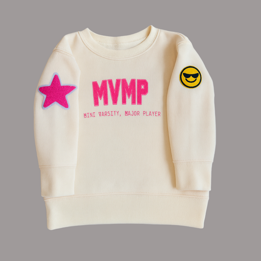 Cream sweatshirt with pink 'MVMP' text and patches on a gray background
